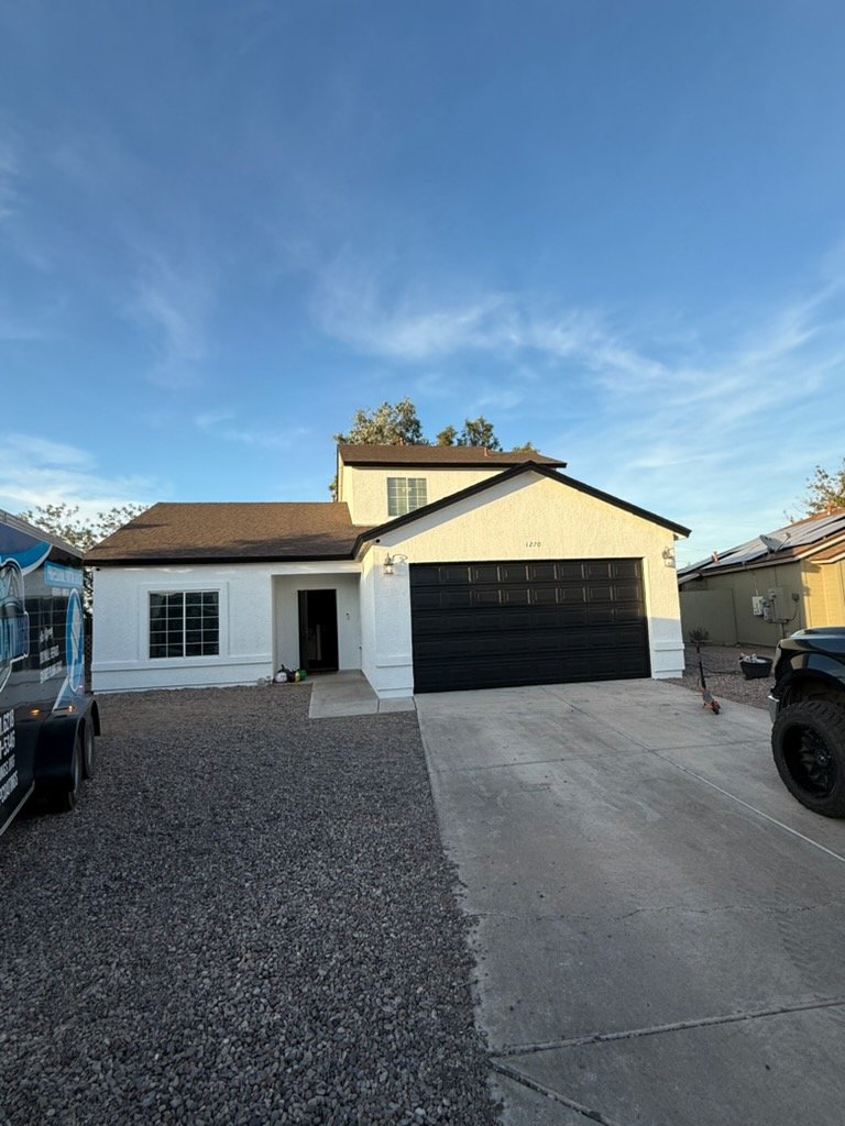 White stucco home with black garage door